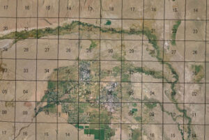 Aerial map grid overlaying farmland, rivers, and a small city with roads and fields.