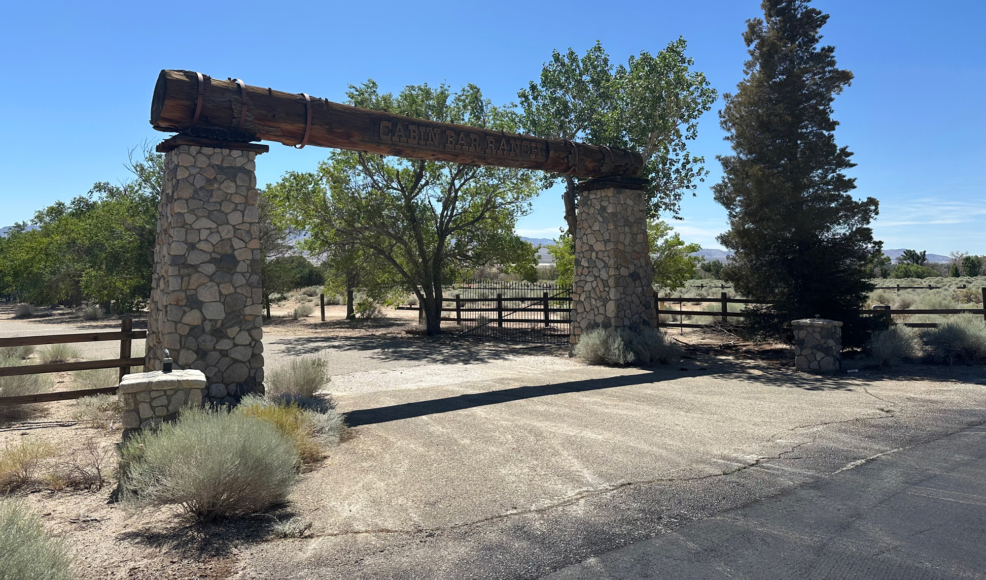 Stone entrance gate labeled "CABIN BAR RANCH" with trees and dry brush in the background.